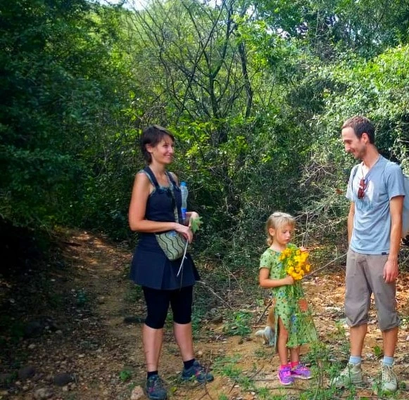 Family standing on a forest trail during a guided nature walk surrounded by green trees and plants